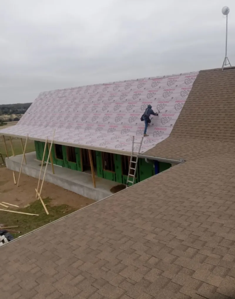 Worker preparing underlayment for a metal roof installation in Rolla
